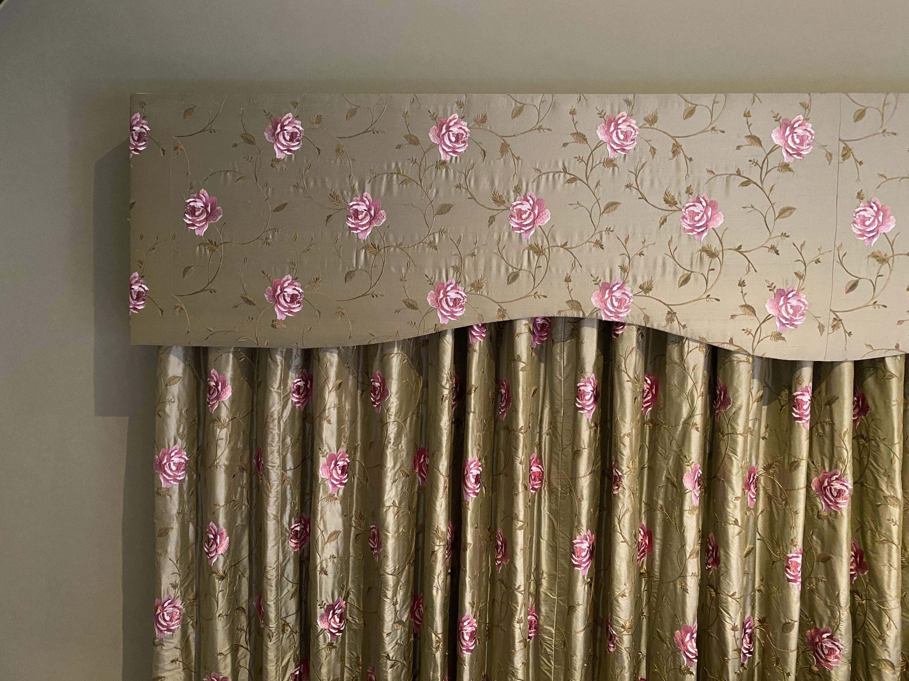 A pair of embroidered woven silk curtains, with pelmet, decorated with pink roses on a eau de nil ground, drop 2.3m, made to generously fit an aperture of 4m width